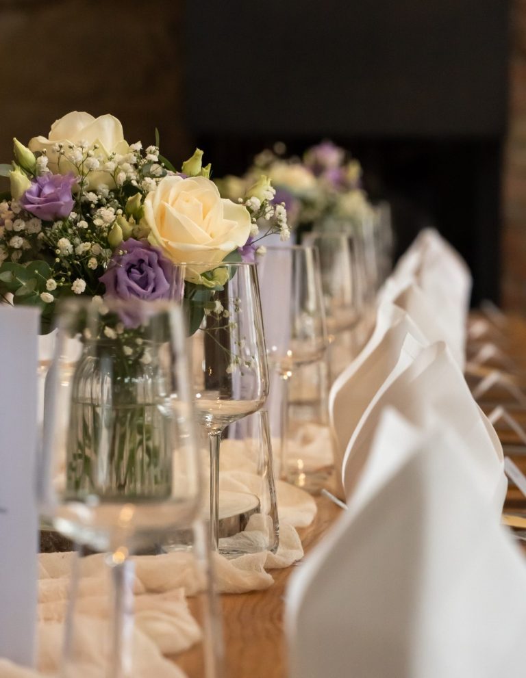 Ein eleganter Tisch mit Blumenarrangements und Gläsern, festlich gedeckt.
